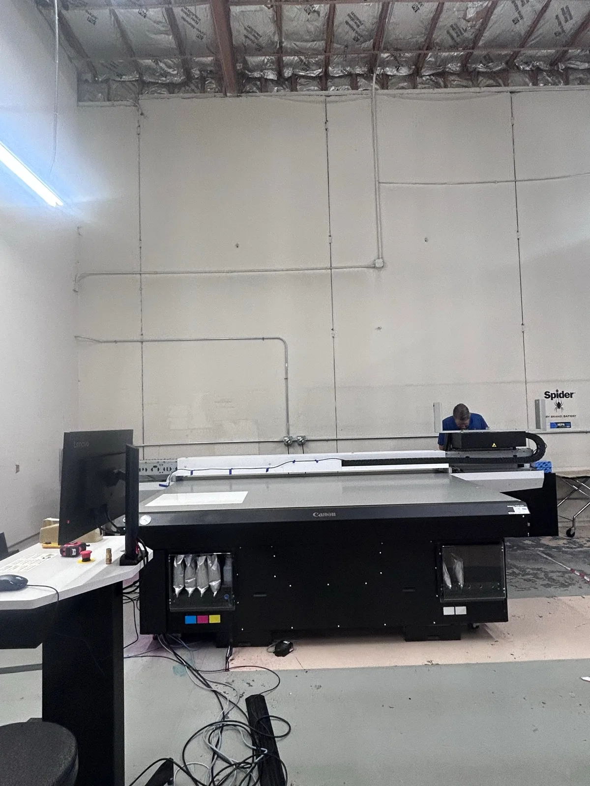 Front view of the installed Canon Arizona flatbed printer with its operator workstation and ink compartments